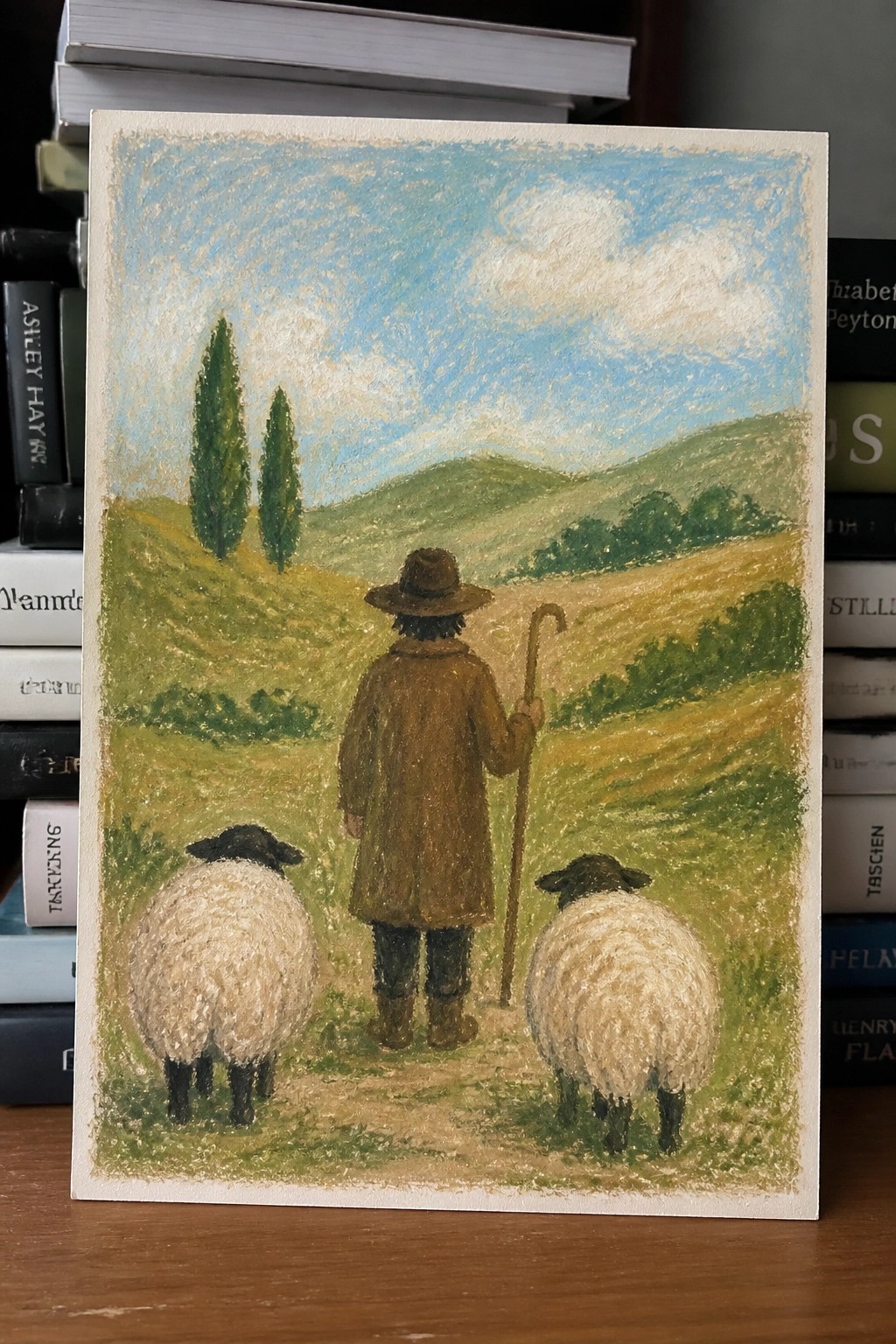 Shepherd in brown coat and hat with staff walks with two sheep through green hills