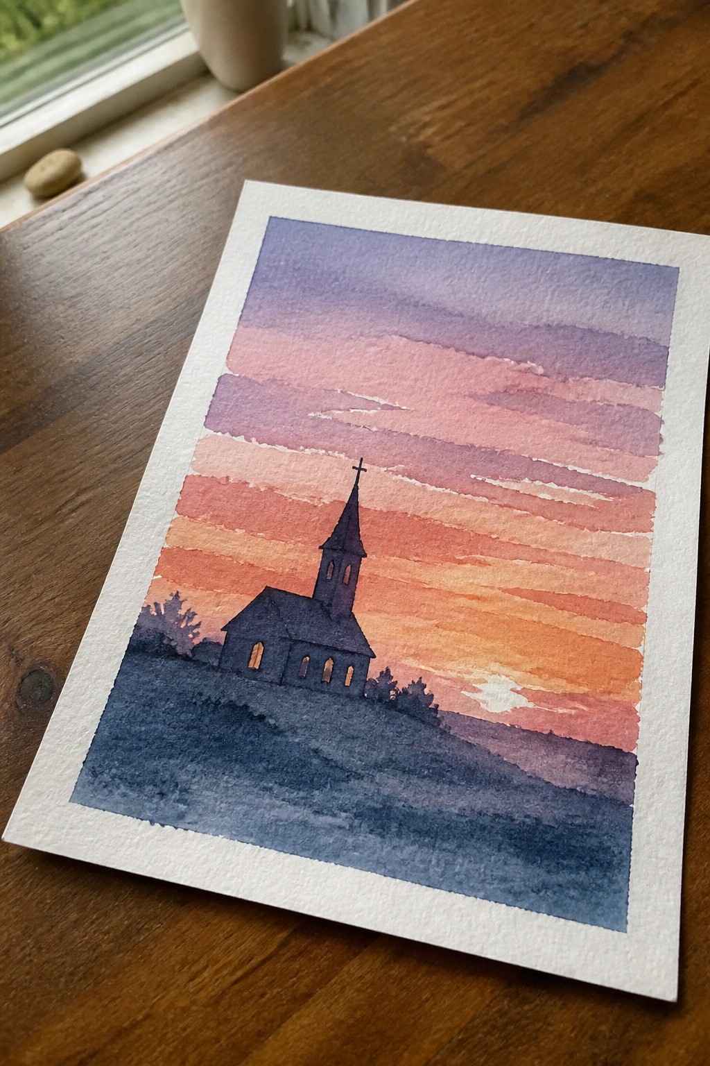 Watercolor painting of silhouetted church steeple against vibrant pink-orange sunset stripes.