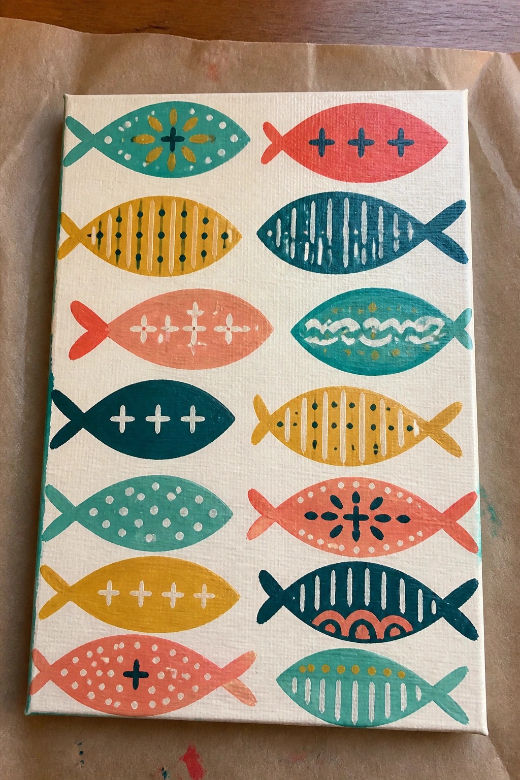 Canvas with rows of colorful patterned fish in teal, red, yellow, and orange.