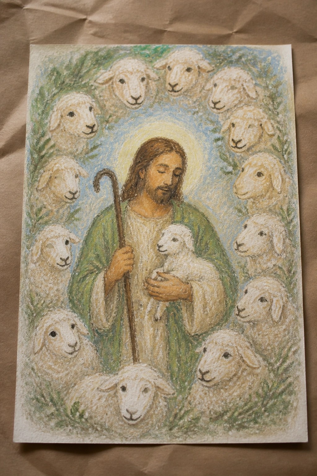 Haloed shepherd in green robe holds lamb and crook amid flock of sheep