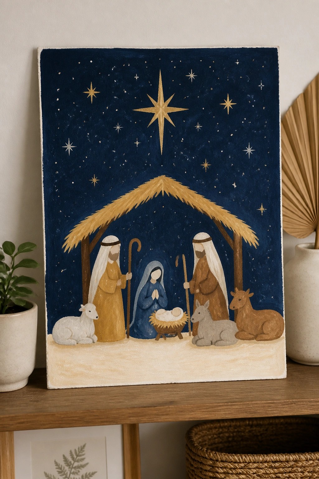 Folk-art nativity with robed figures, animals, and golden star above manger on dark blue.