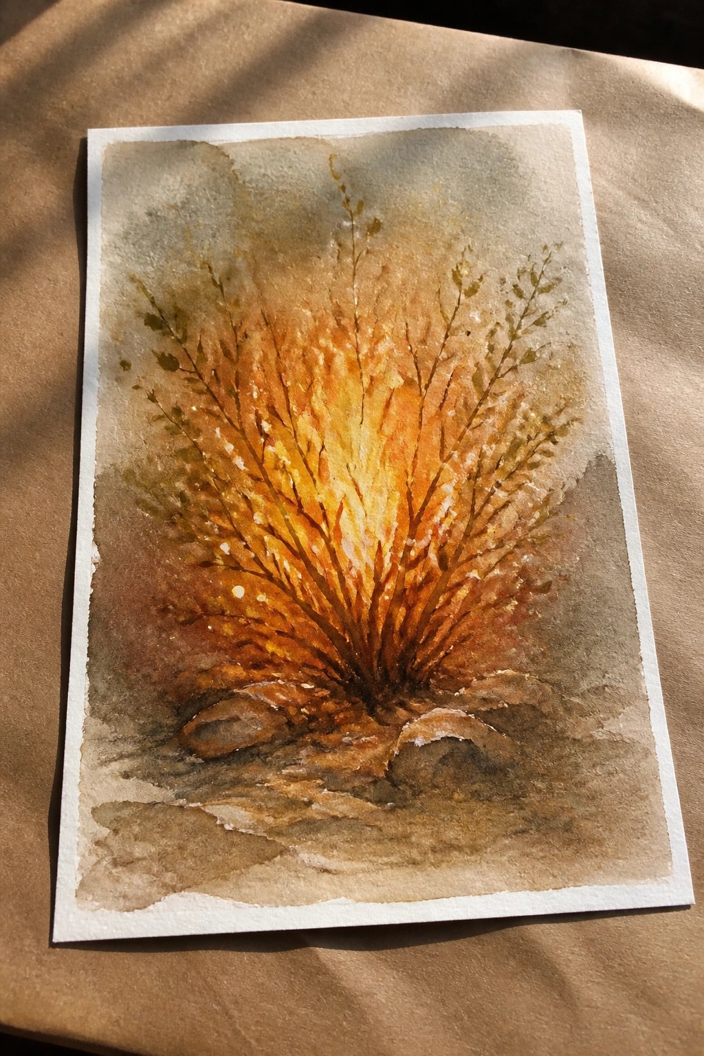 Watercolor of fiery orange bush with rocks at its base