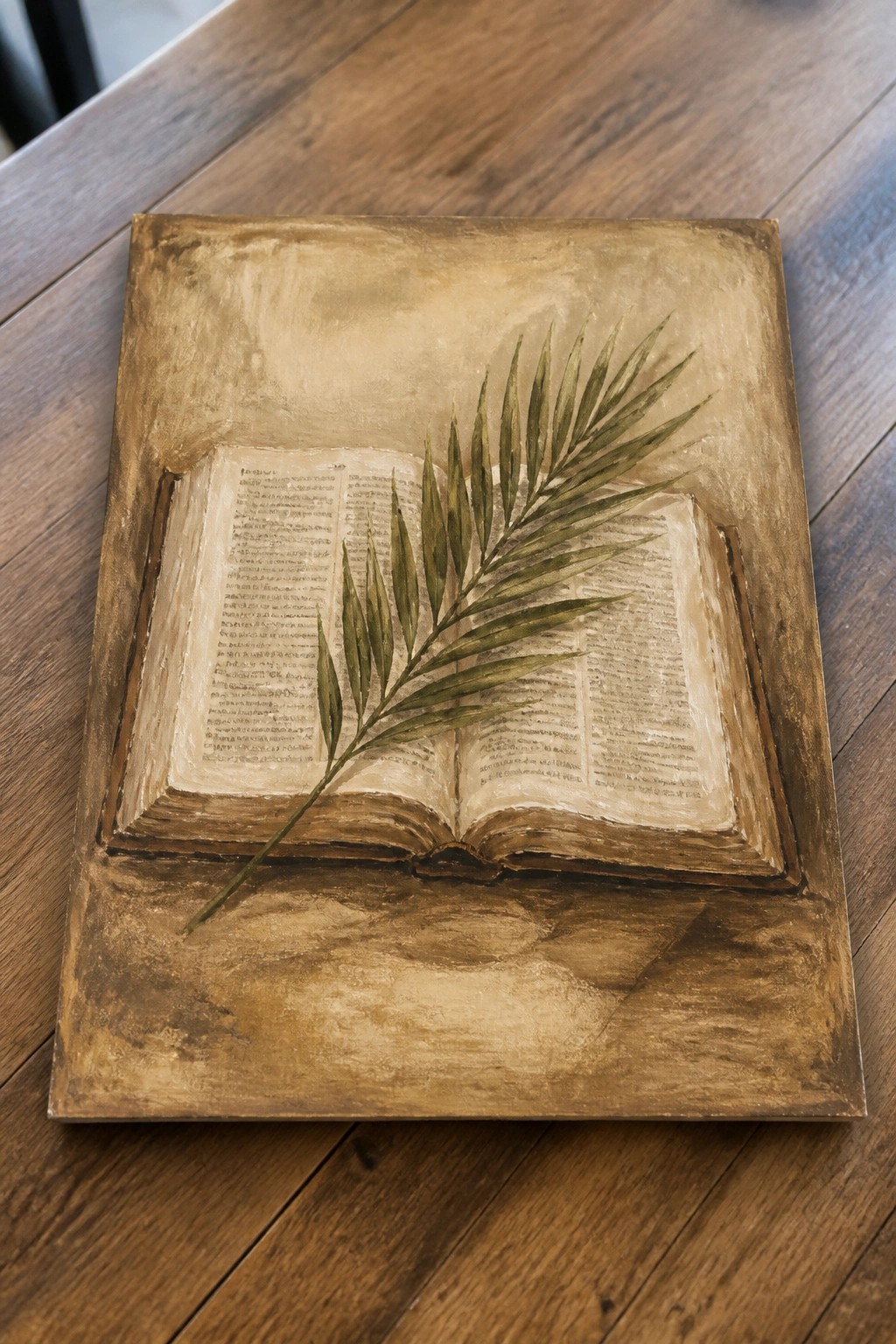 Open book with green palm frond on textured golden background over wood