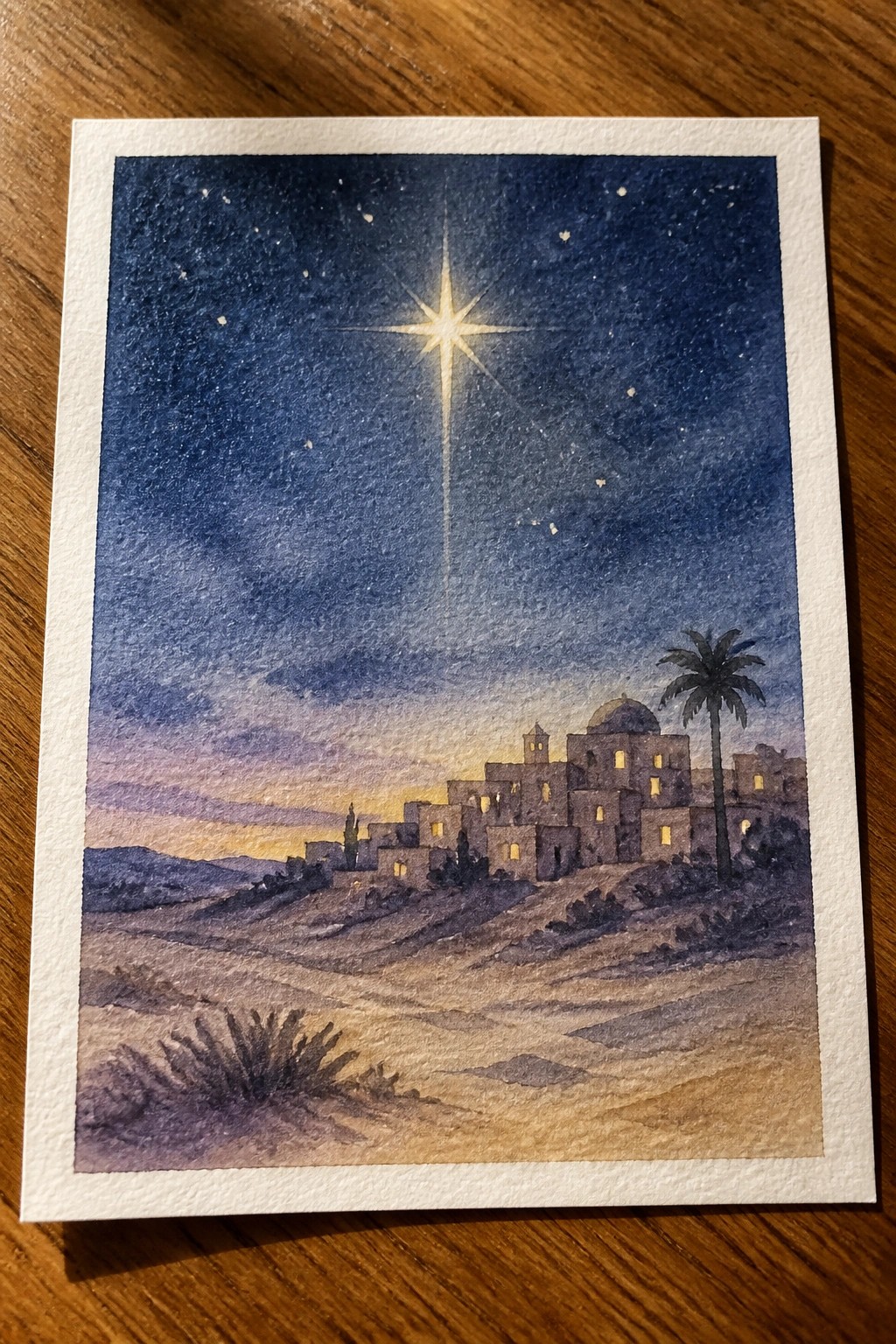 Watercolor of bright star over desert village with palm tree and glowing windows at night