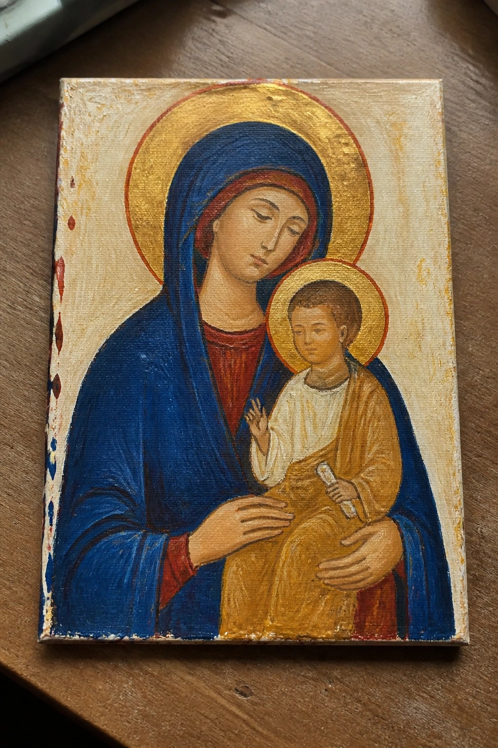 Byzantine icon of blue-robed Madonna cradling haloed Christ Child holding a scroll.
