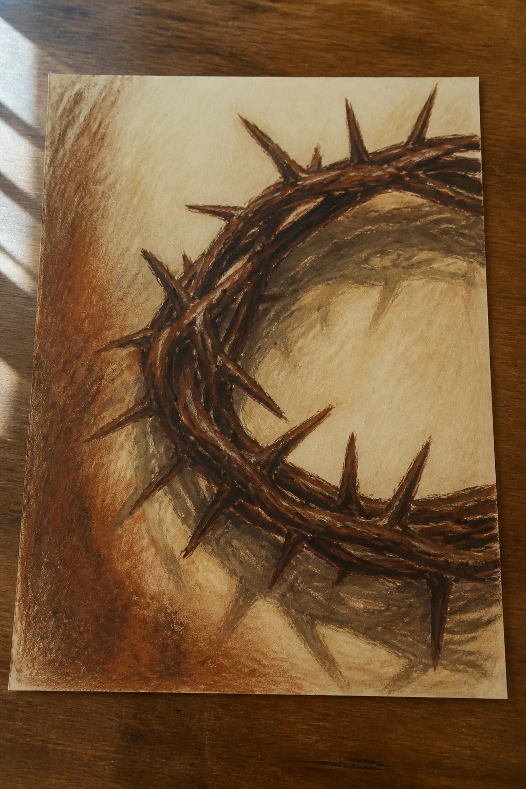 Brown crown of thorns with sharp spikes sketched on paper atop wood