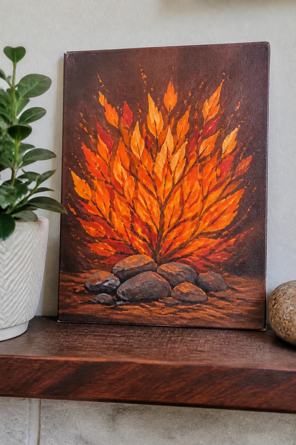 Vibrant painting of a fiery orange-red autumn tree with rocks on a shelf.