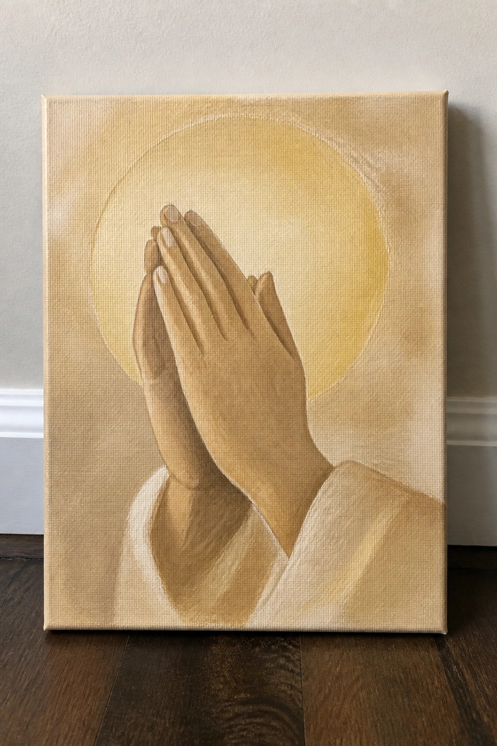 Painted praying hands in white sleeves before glowing yellow orb on canvas