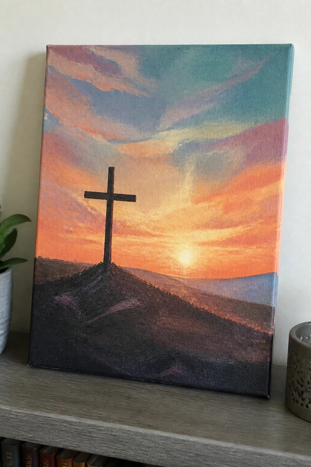 Silhouetted cross atop a hill against a vibrant orange-pink sunset sky.