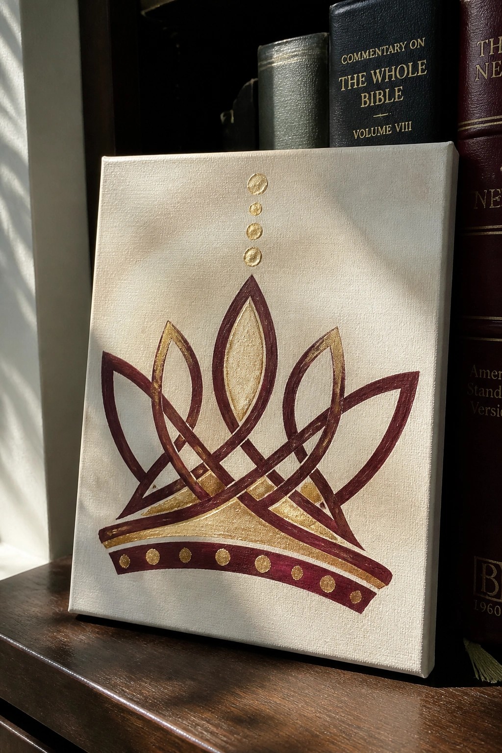 White canvas with maroon and gold crown painting beside leather-bound books.