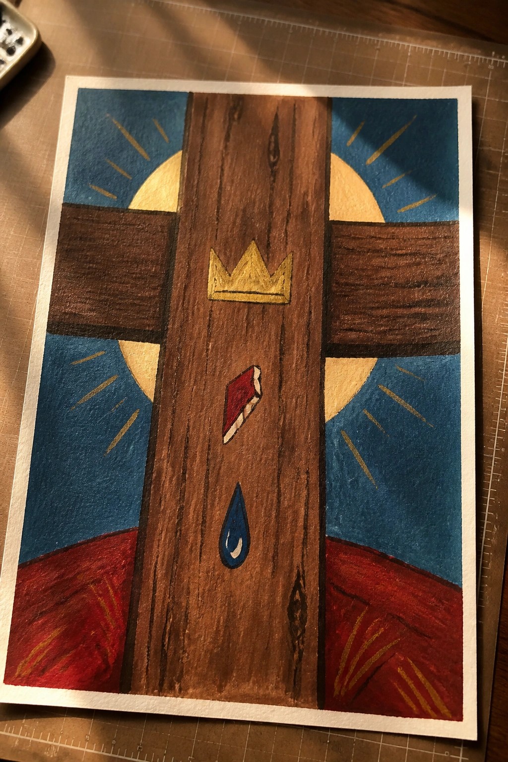 Wooden cross with golden crown, red object, blue teardrop against blue sky with yellow rays and red ground.