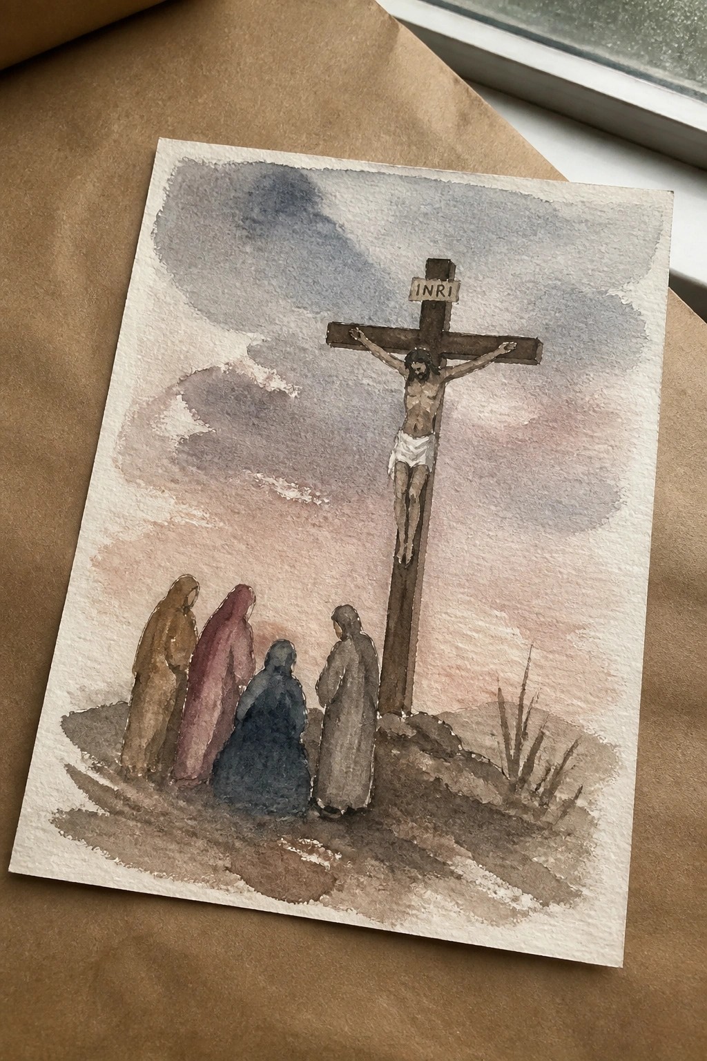 Watercolor of Jesus on cross with INRI sign, four robed women below on hill