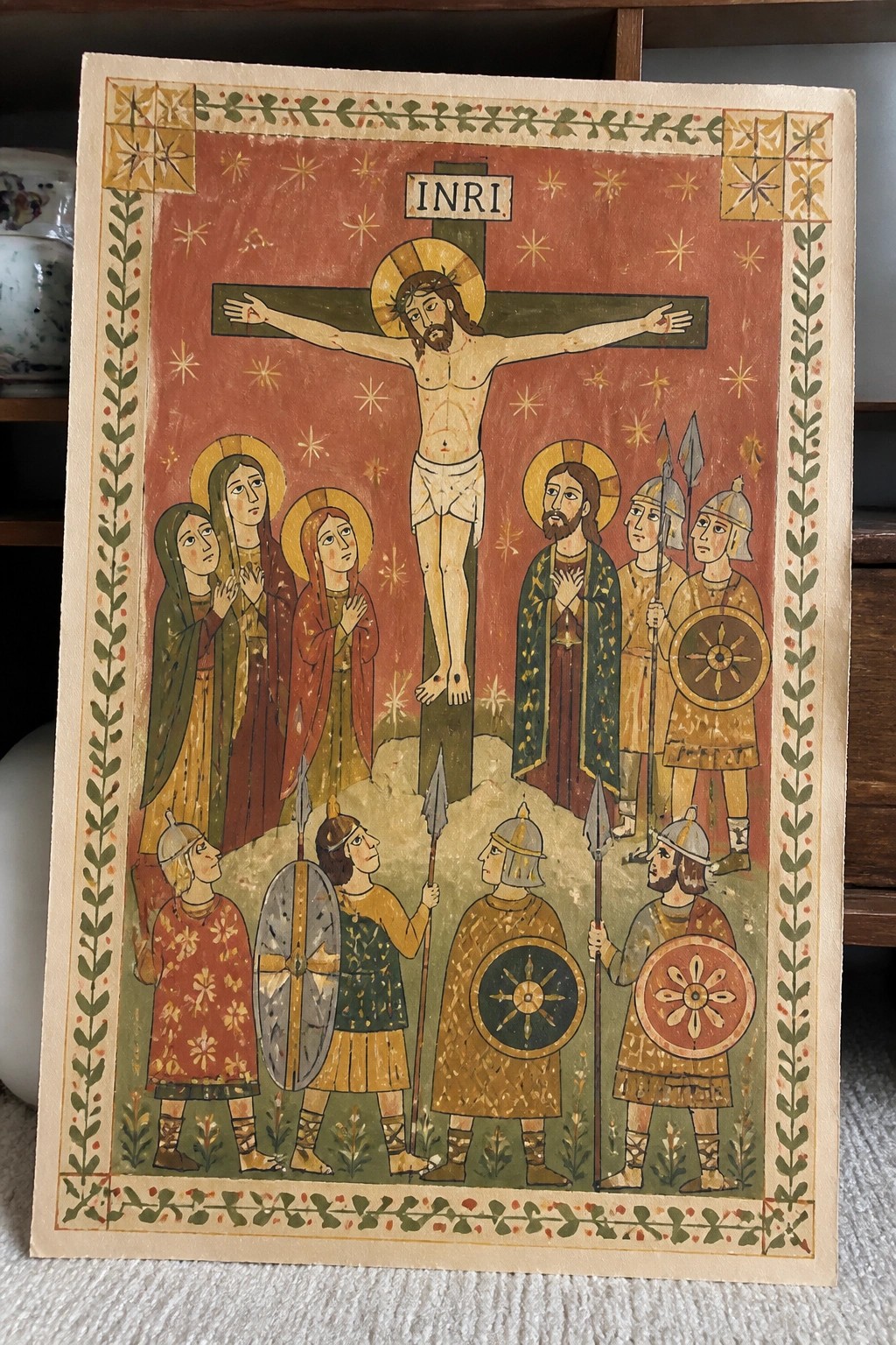 Medieval folk-art crucifixion with INRI, haloed women, and helmeted soldiers holding spears and shields.