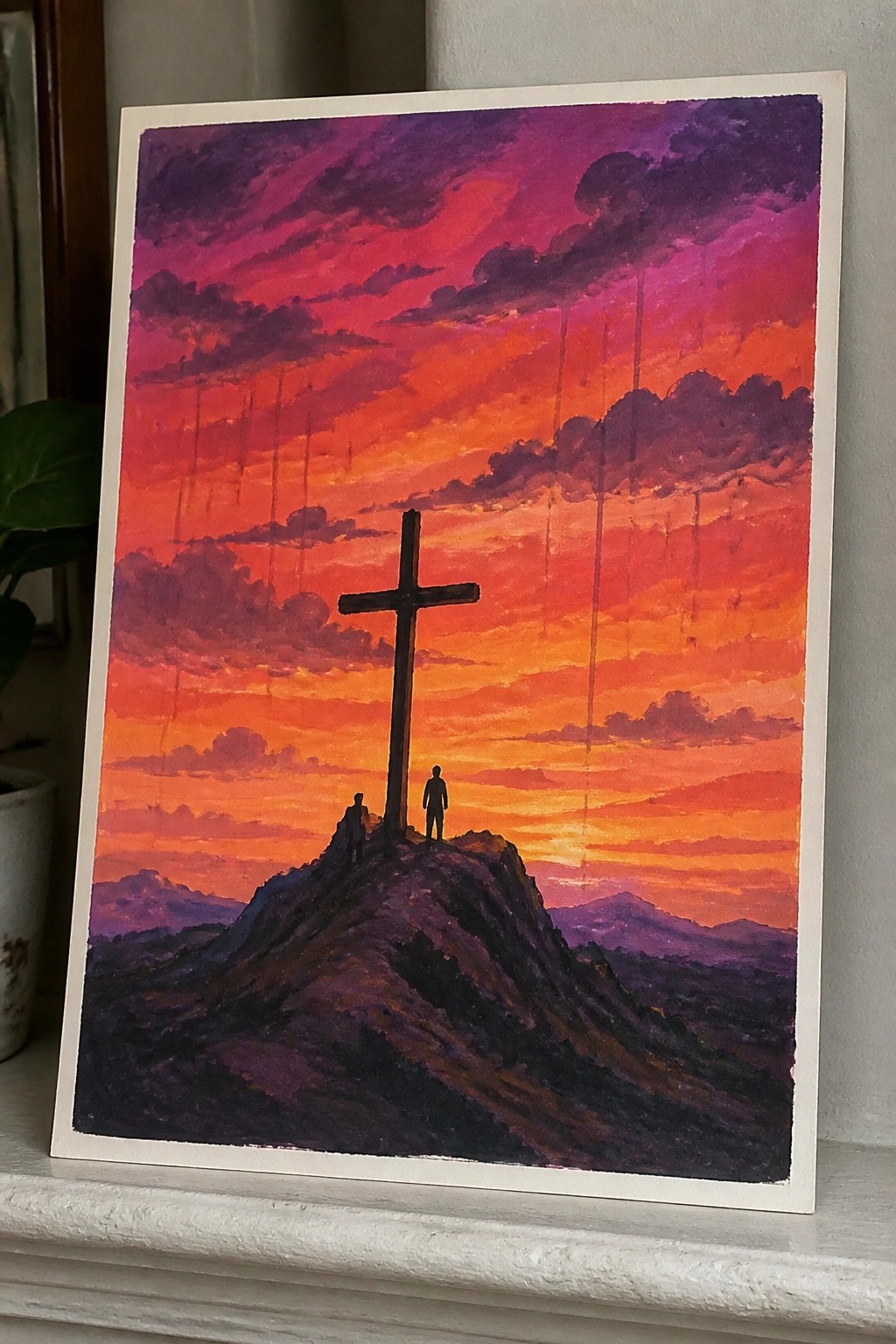 Silhouetted cross and two figures atop mountain under vibrant orange-purple sunset sky with clouds