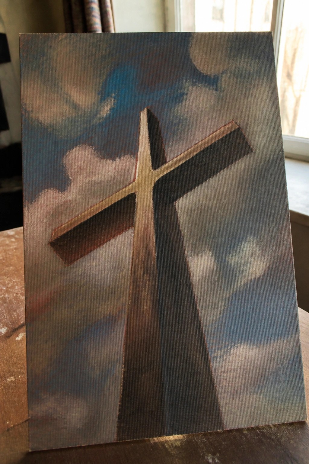 Canvas painting of a wooden cross against a dark stormy sky with sun