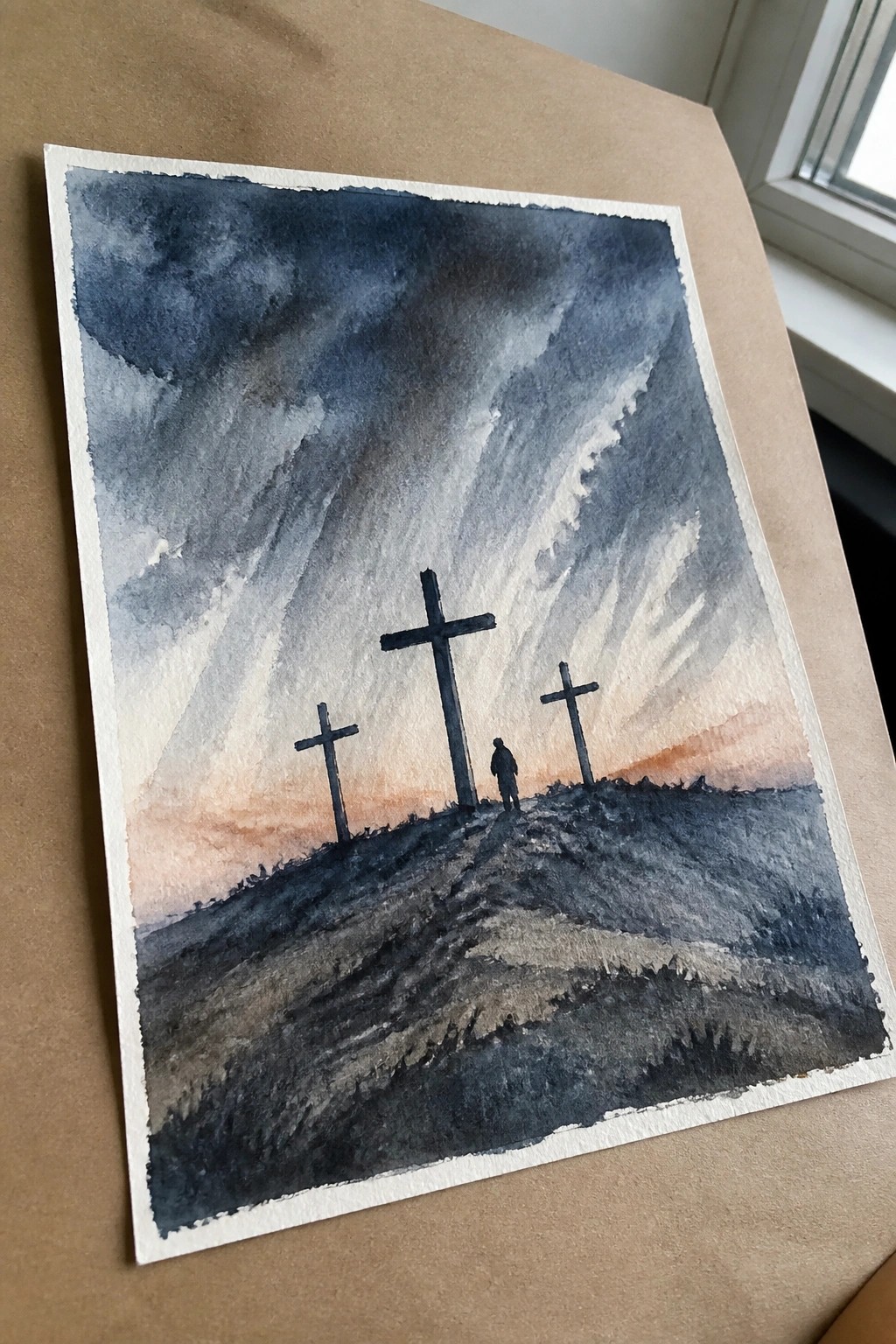 Watercolor of three crosses and a lone figure on a hill beneath stormy sunset skies