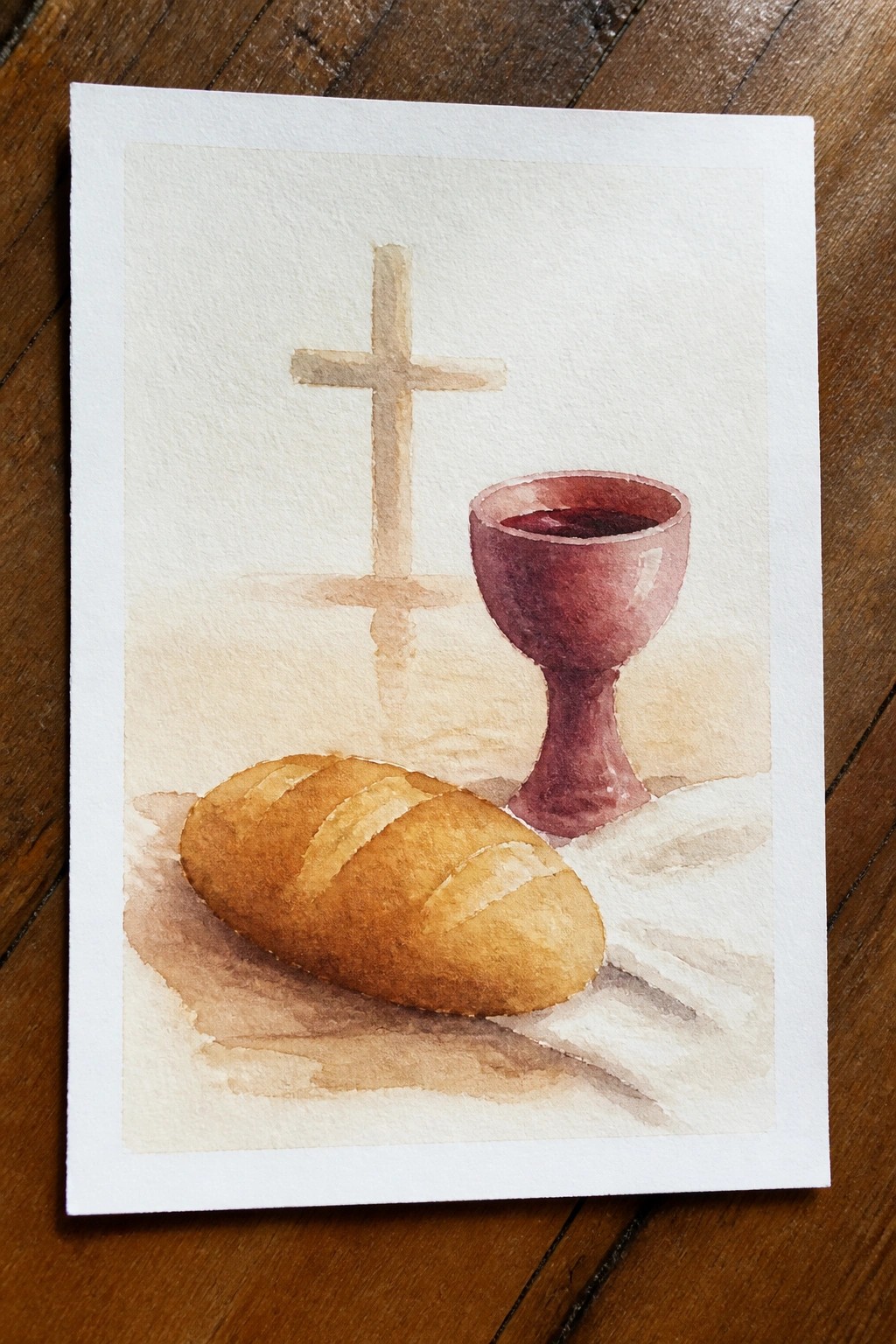 Watercolor still life of a bread loaf, wine-filled chalice, and cross on white paper resting on wood.