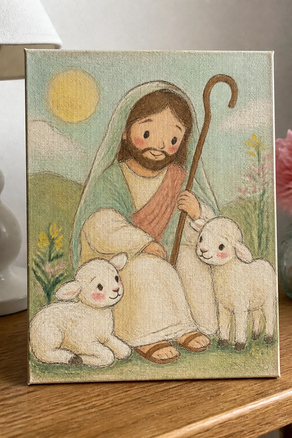 Jesus in green robe holds staff beside two white lambs in sunny meadow