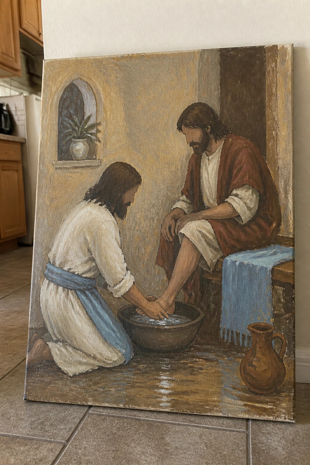 Jesus in white robes with blue sash washes seated man's feet in red robe beside basin