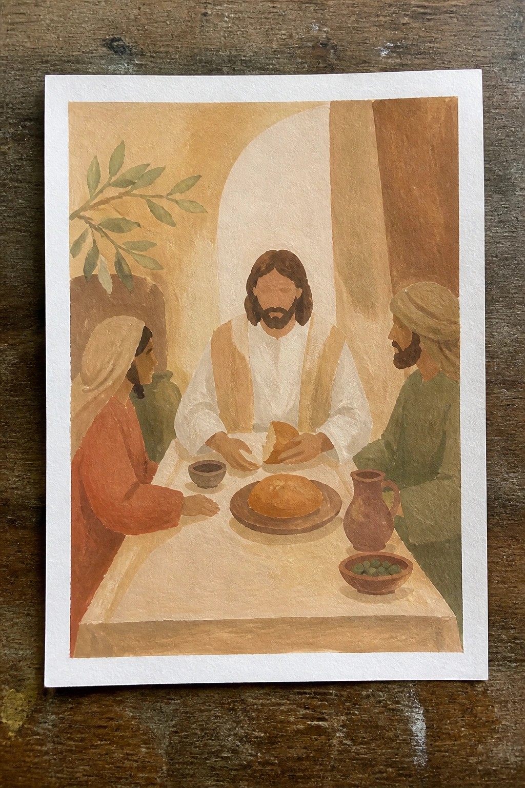 Jesus breaks bread with a woman in red and man in green at a table
