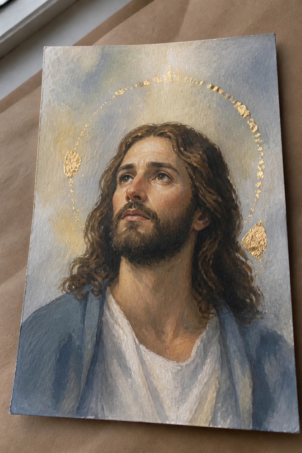 Bearded man with long hair in blue and white robes gazing upward, gold leaf halo.