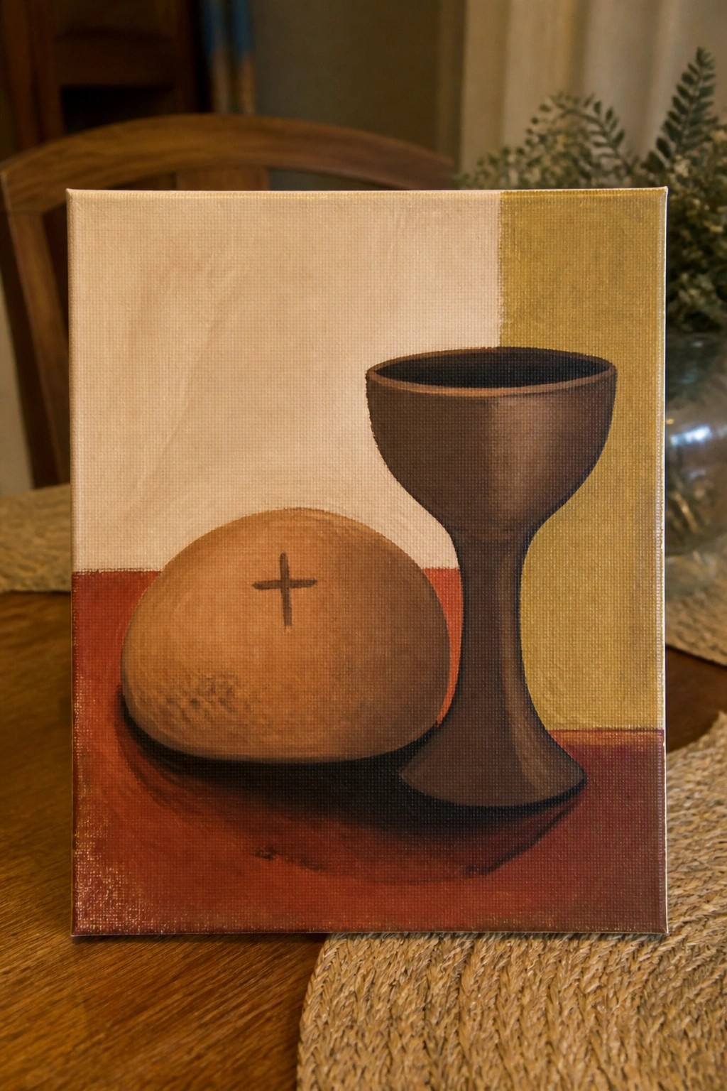 Still life painting of brown chalice beside bread marked with cross on red surface