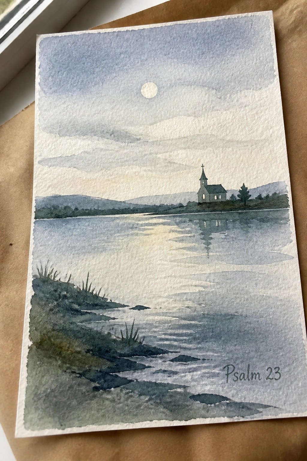 Watercolor of moonlit lake with church reflection, hills, and Psalm 23 text.
