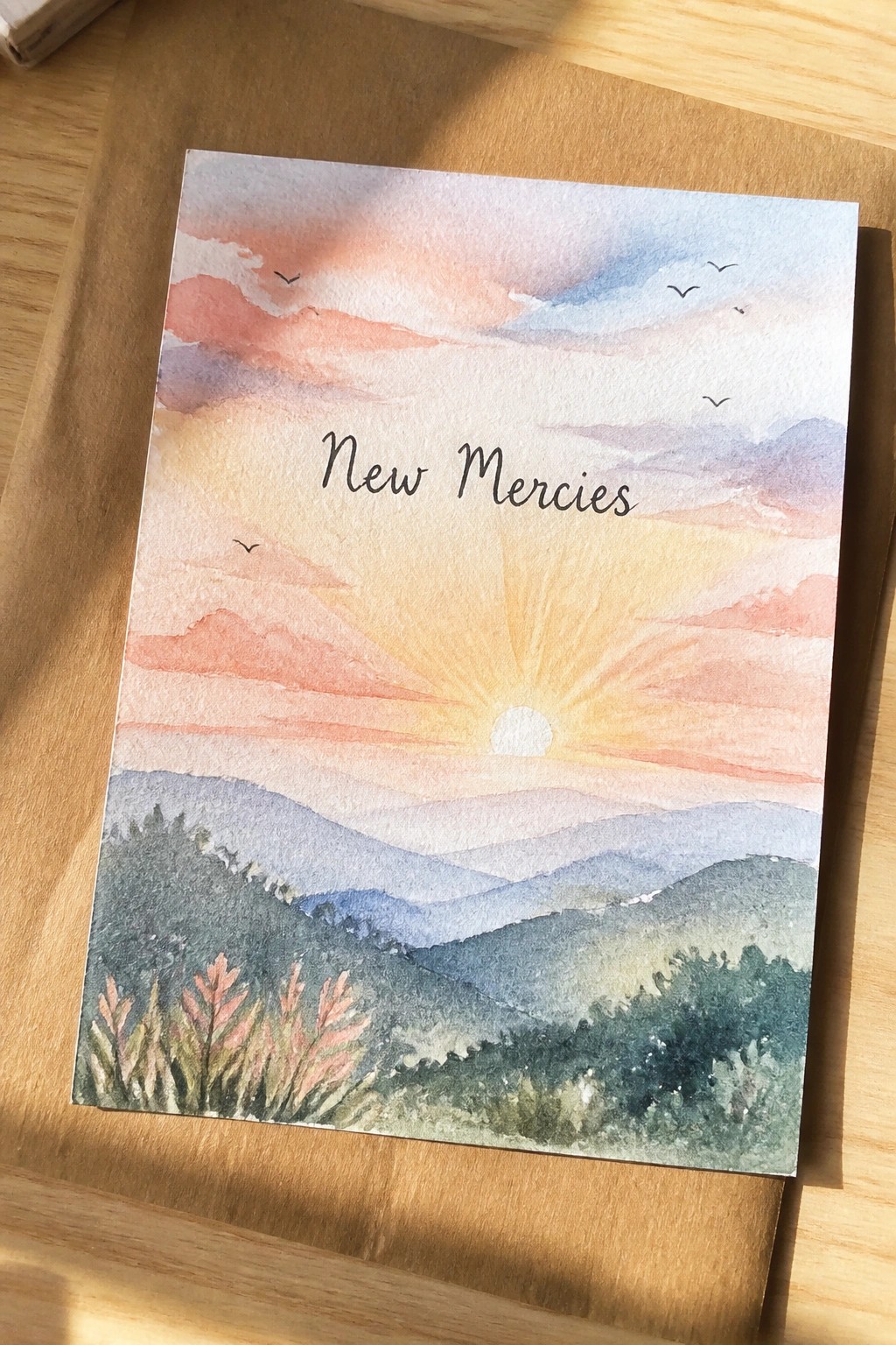 Watercolor sunset landscape with sun rays, mountains, birds, and 