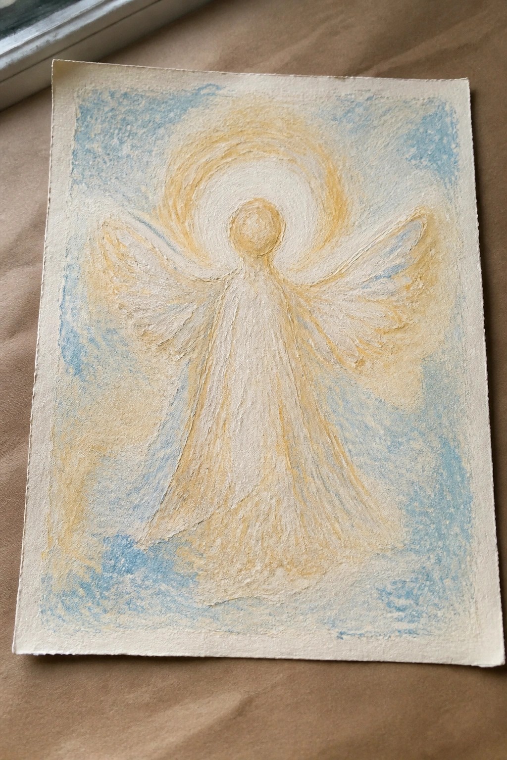 Radiant white angel with spread wings and glowing halo amid swirling blue and yellow.