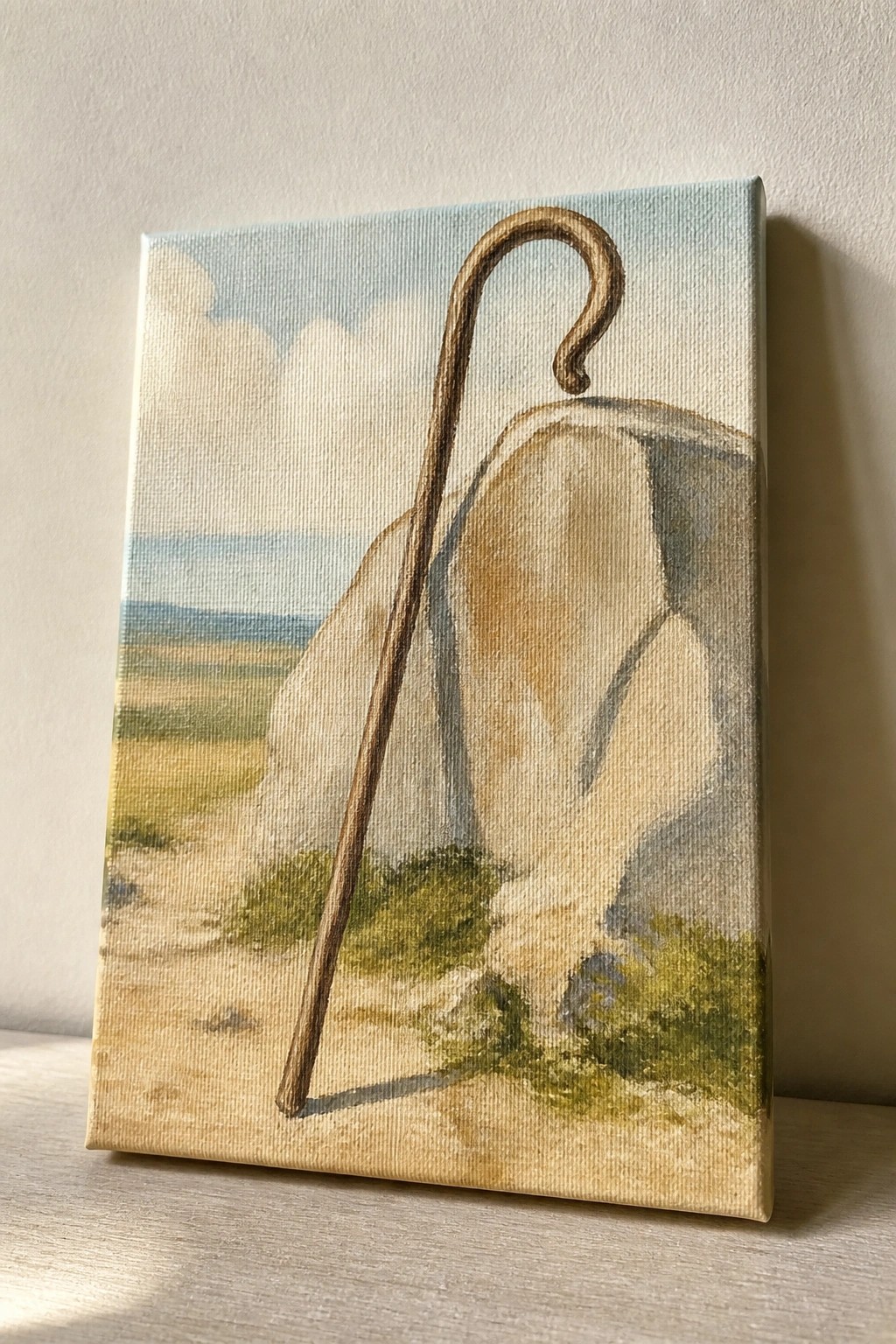 Painting of wooden shepherd's crook leaning on large rock in rural landscape