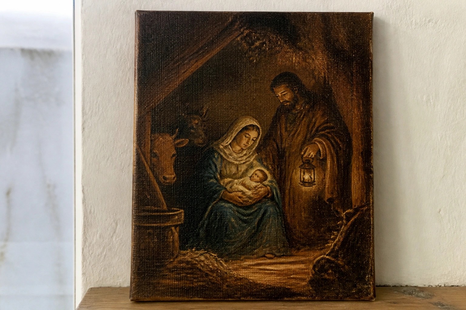 Painting of Mary in blue holding swaddled infant beside Joseph with animals in lantern-lit stable