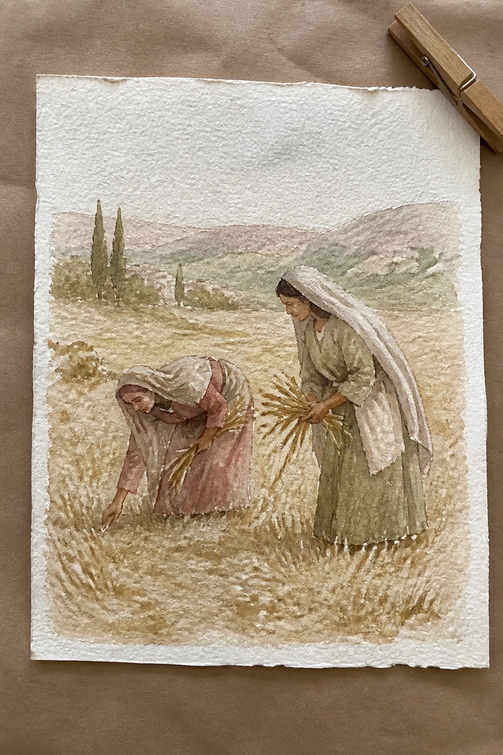 Women in headscarves and long dresses harvest wheat in a muted watercolor landscape with clothespin.