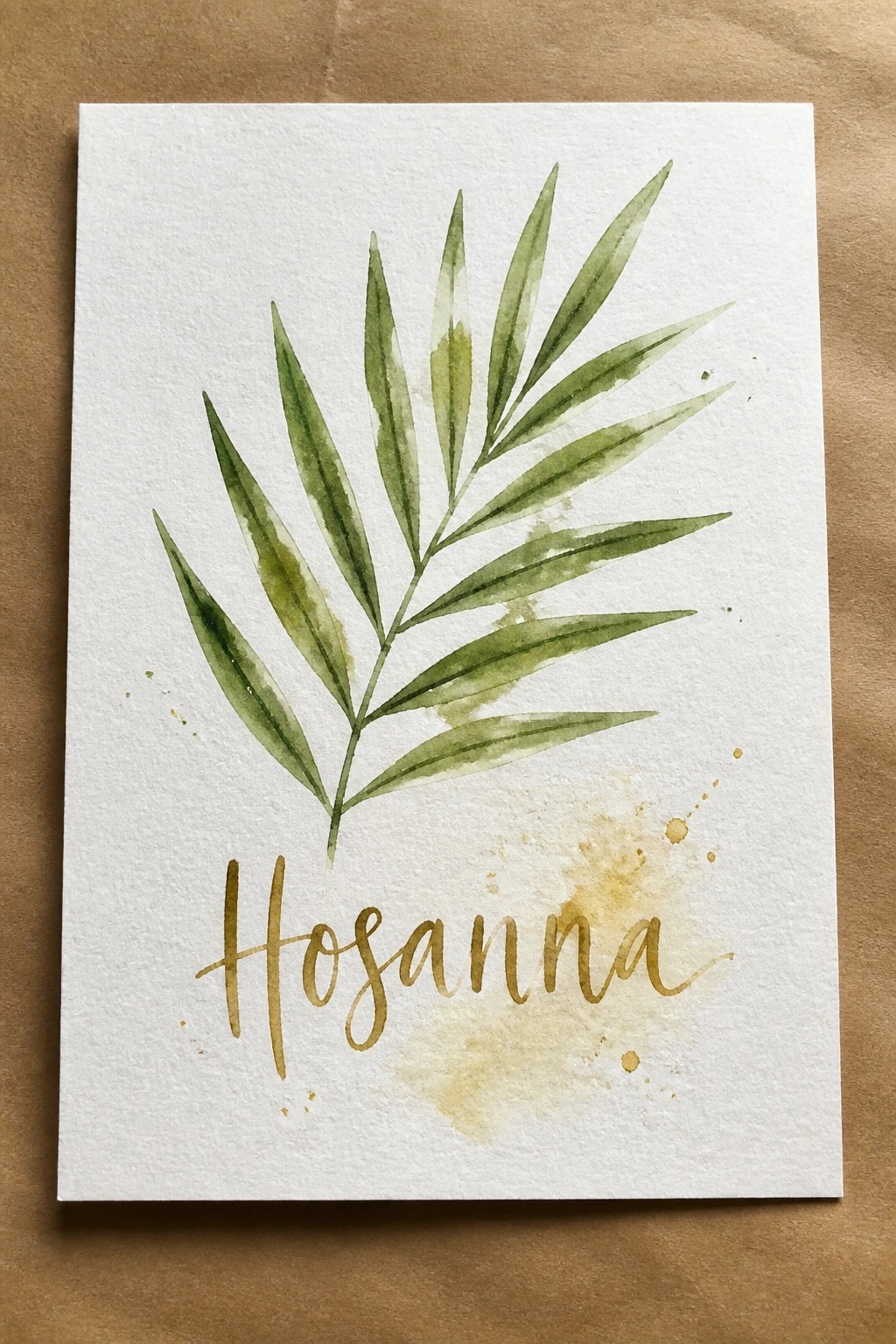 Green watercolor leaf with gold cursive Hosanna and splatters on white paper