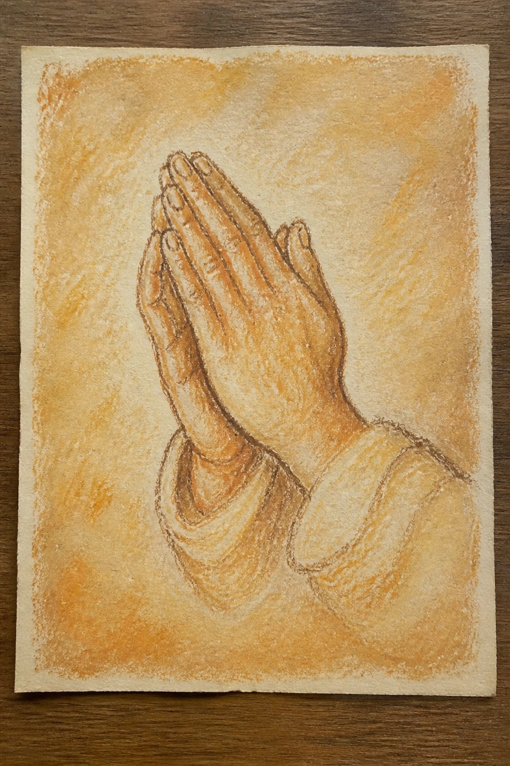 Hands clasped in prayer with robe sleeves, in warm orange pastels.