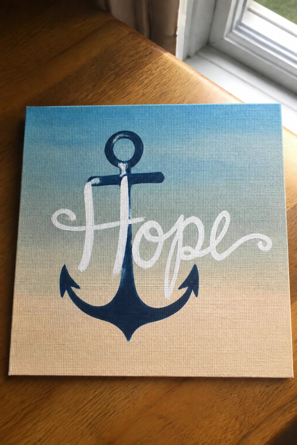 Canvas painting of navy blue anchor with white cursive 