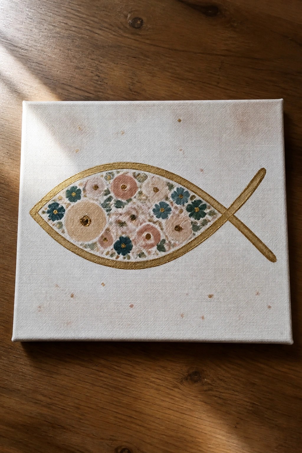 Floral fish symbol with pink and blue blooms in gold on white canvas.