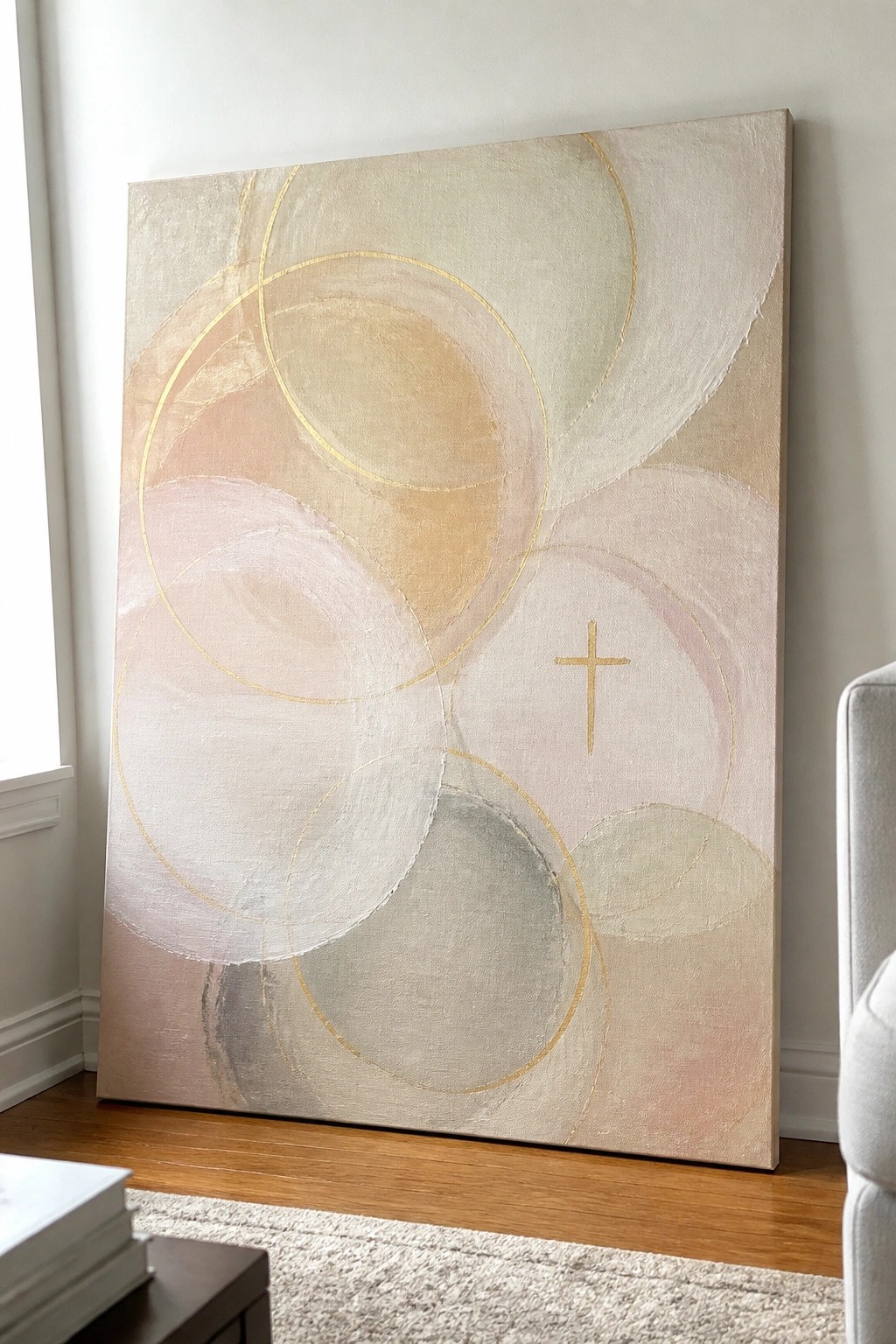 Abstract painting with soft pastel circles, gold outlines, and small cross on canvas.