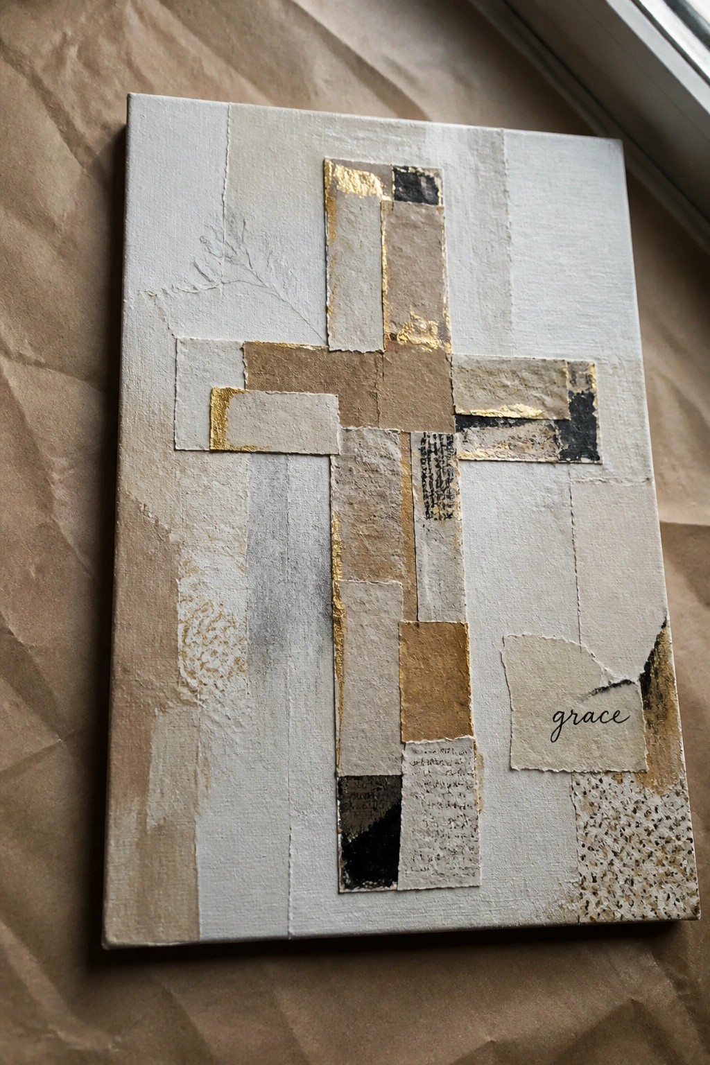 Mixed-media cross collage on canvas with gold foil, beige tones, and cursive grace text