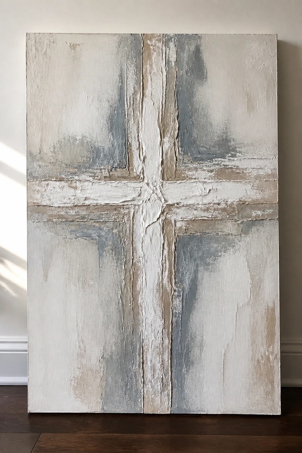 Textured abstract painting with central cross in white, gray, and beige on wall