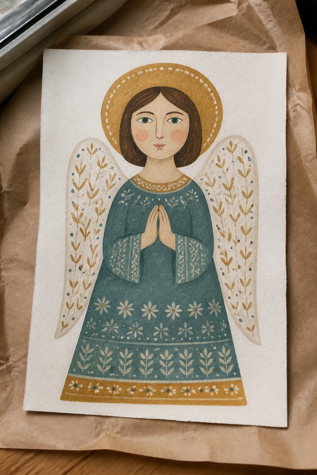 Watercolor angel with brown hair, golden halo, teal patterned dress, and prayer hands