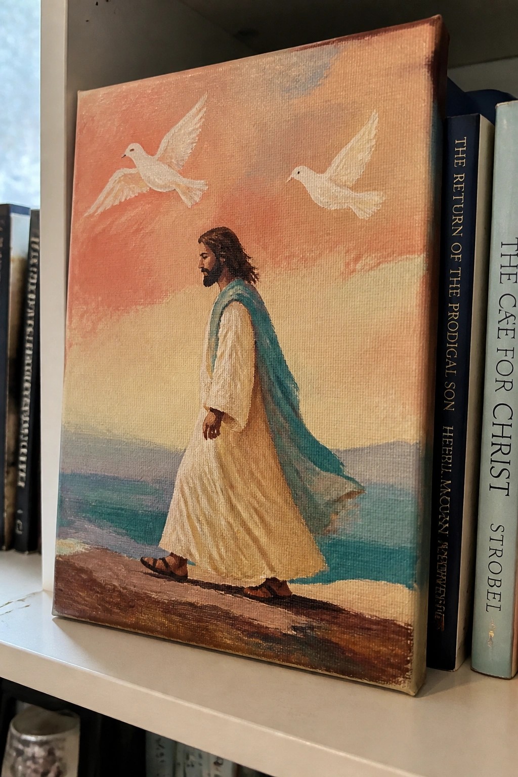 Jesus in white robe with blue cloak walks by sea under orange sky with two white doves.
