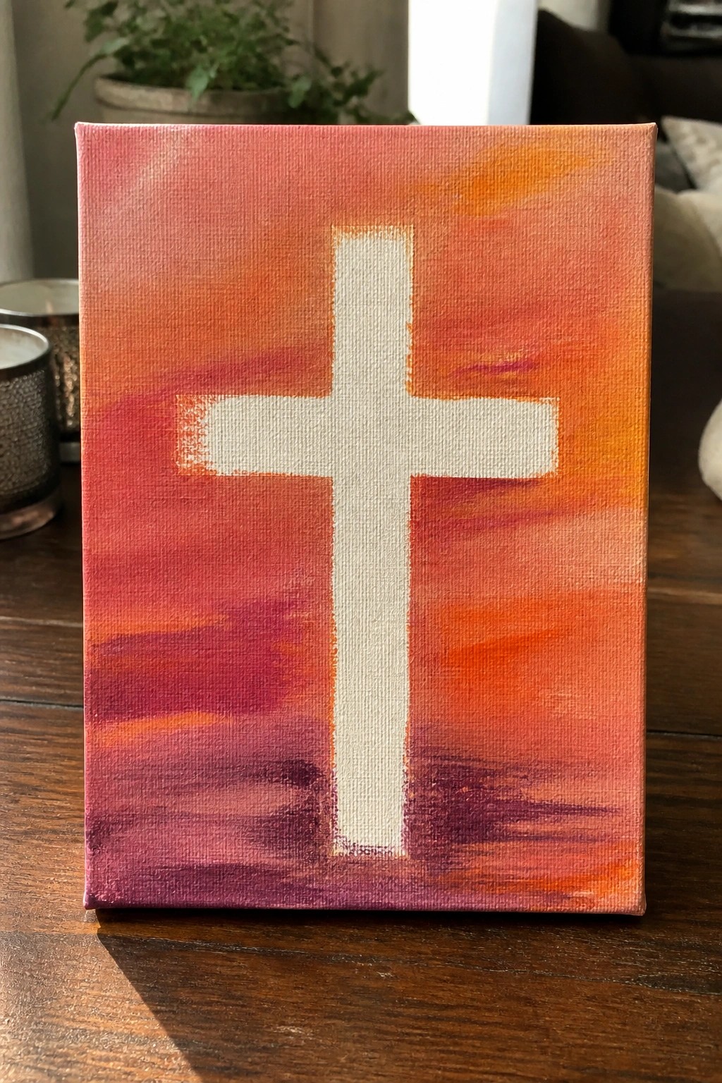 A rectangular canvas shows a white cross centered on a background of blended red, orange, and purple brushstrokes.