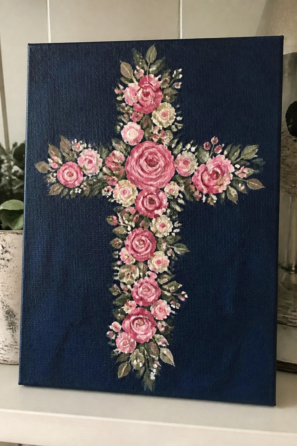 Navy blue canvas with central cross of blooming pink roses and green leaves