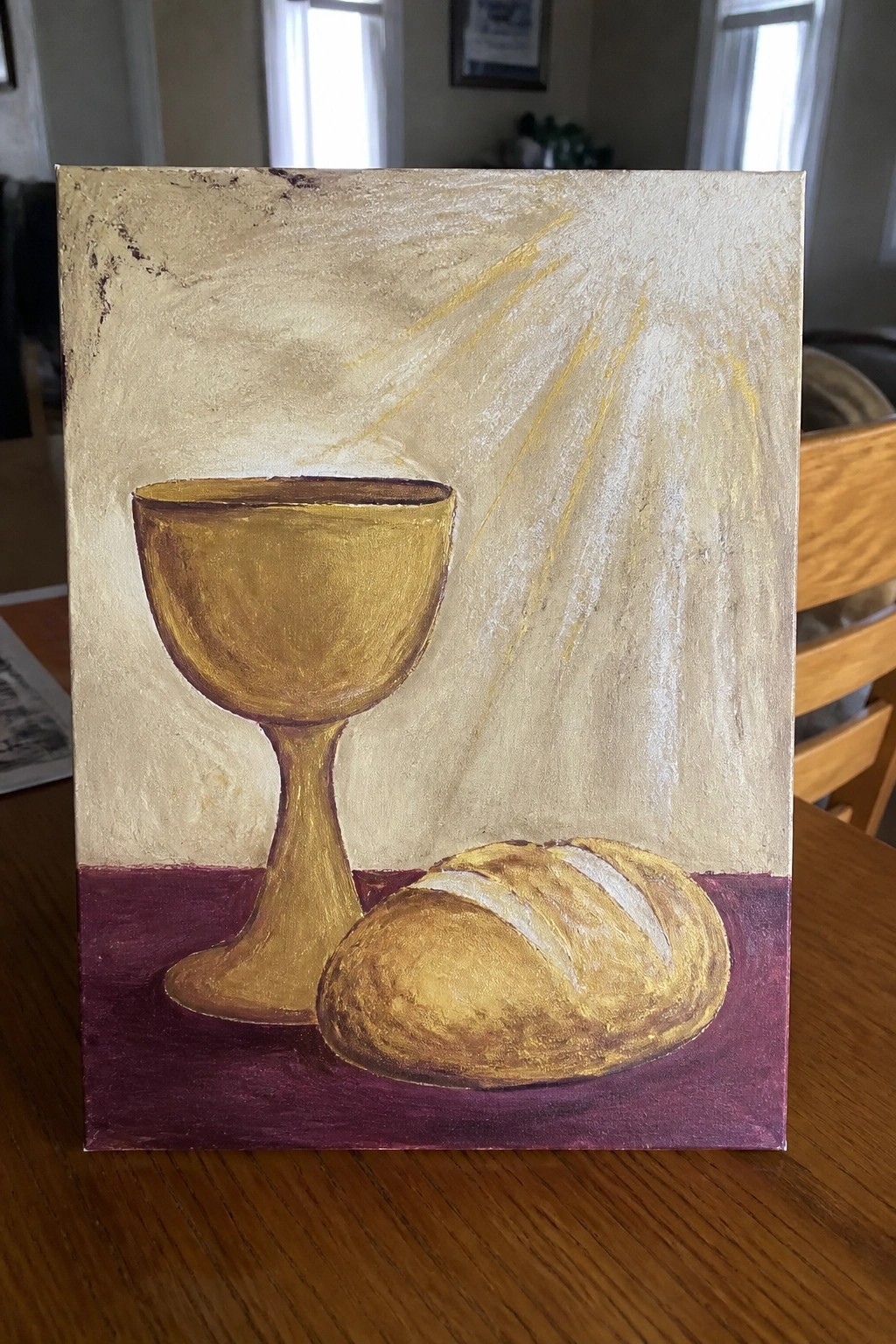 Golden chalice beside bread loaf on purple surface with golden light rays background