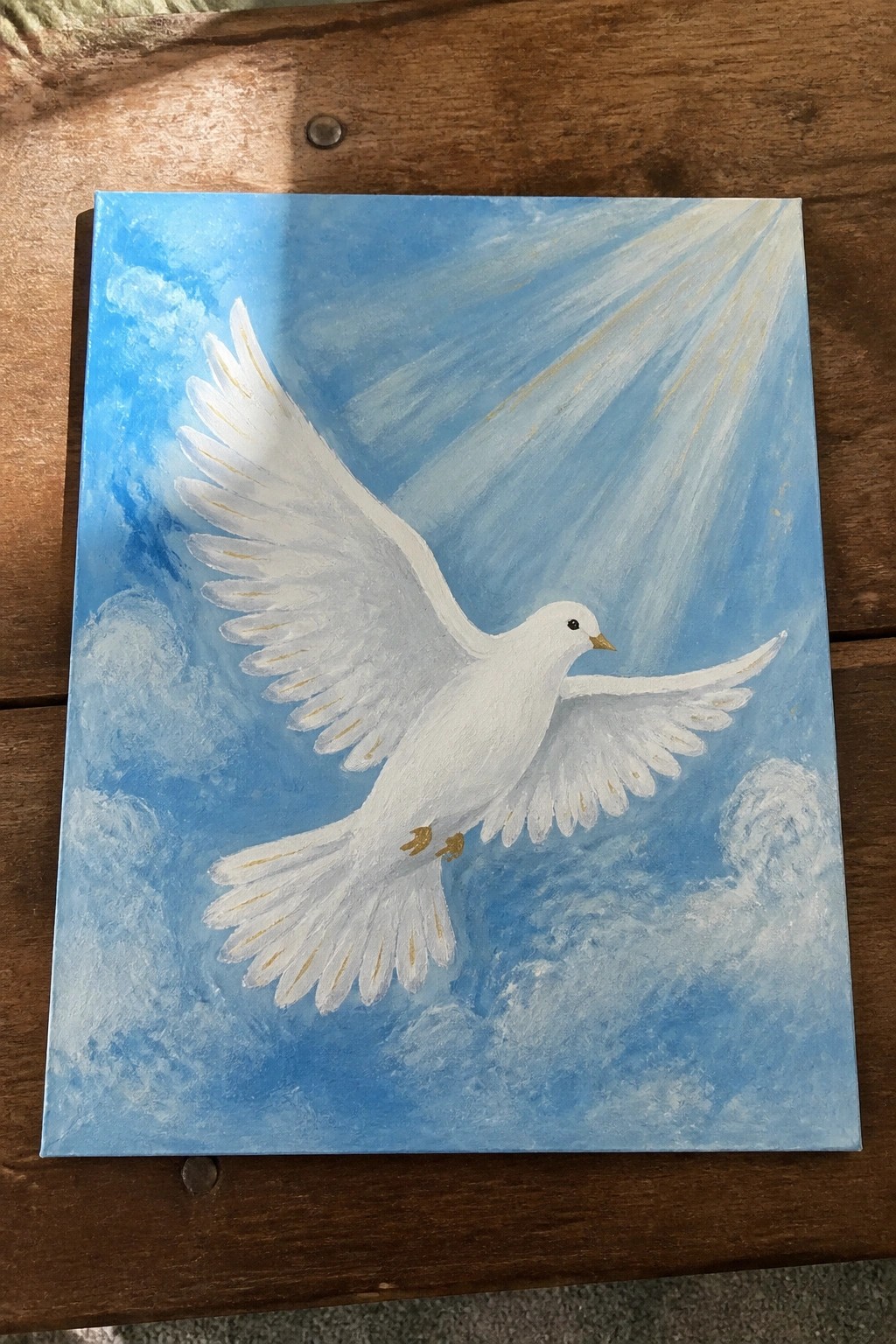 White dove with gold accents soaring in blue sky with clouds and light rays