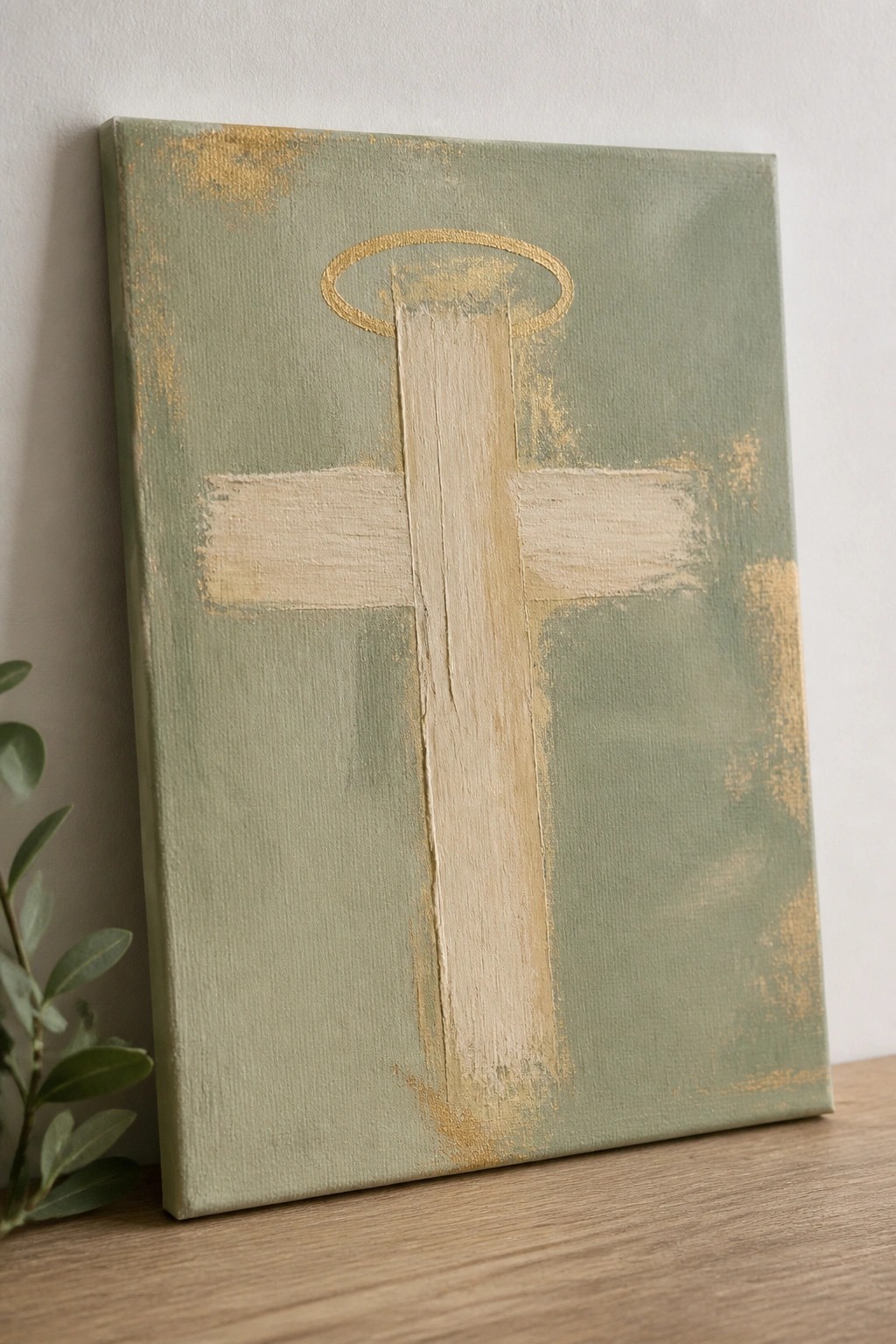 Sage green canvas with beige cross, golden halo, and gold accents on wooden surface