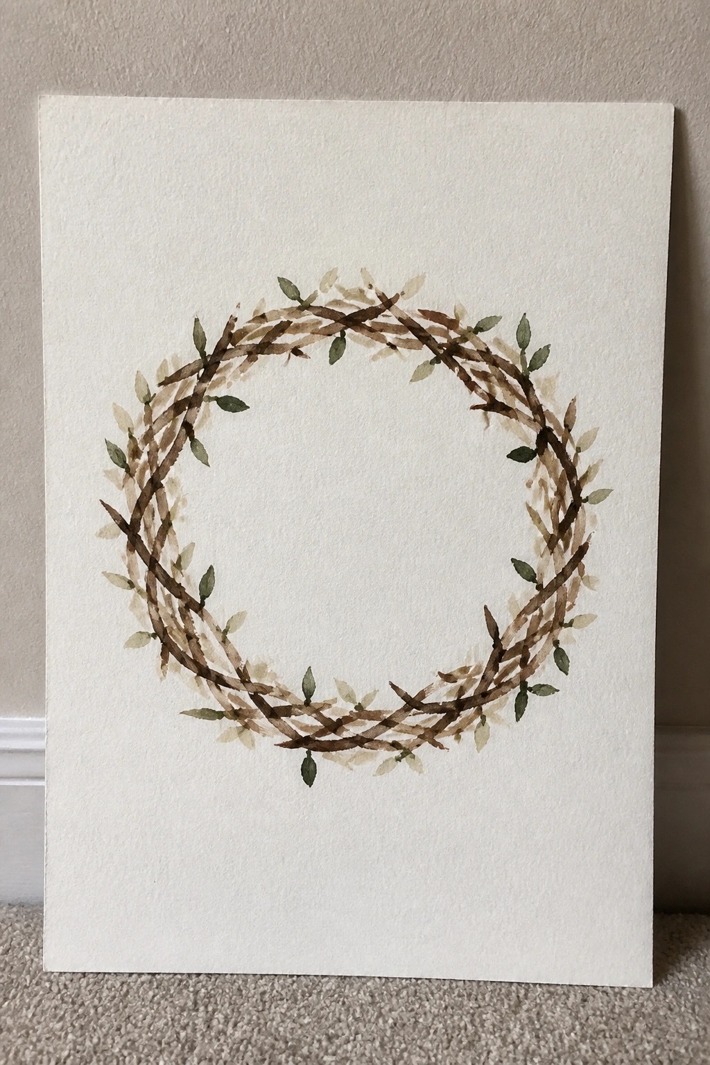 Watercolor wreath of intertwined brown branches with green and beige leaves on white paper