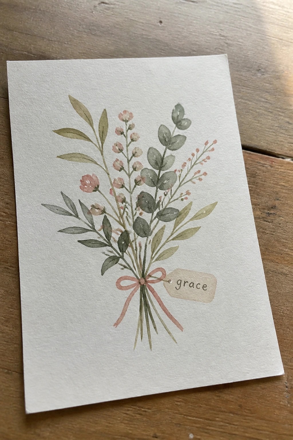 Watercolor bouquet of pink flowers and green leaves tied with pink ribbon and grace tag