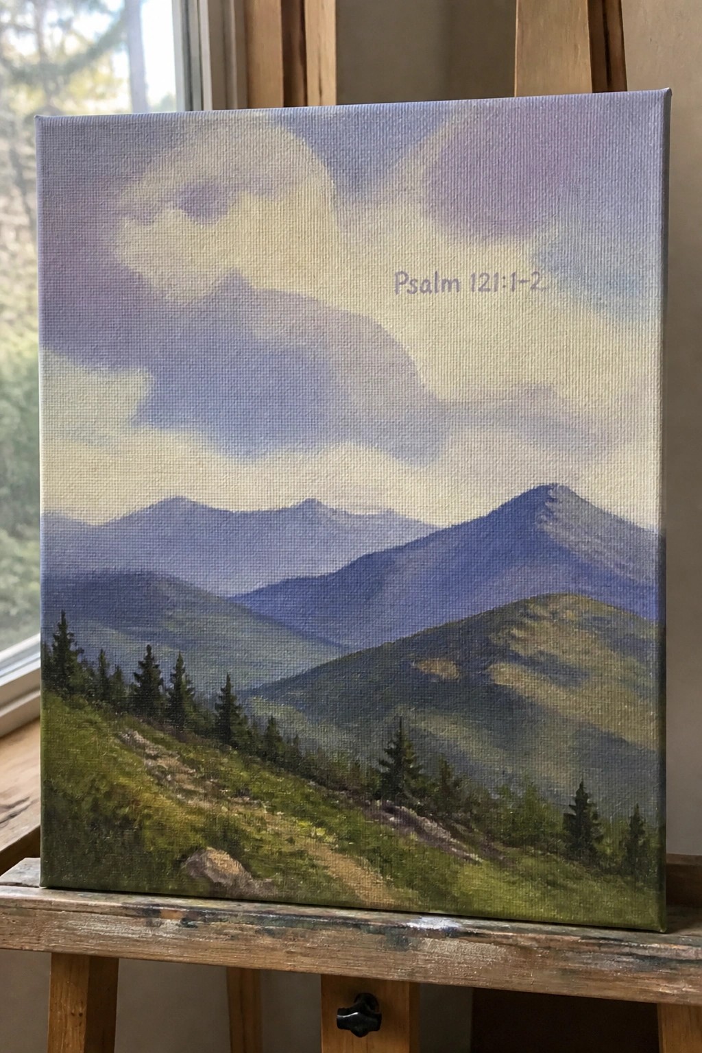 Canvas painting of blue mountains and green hills on wooden easel with Psalm text.