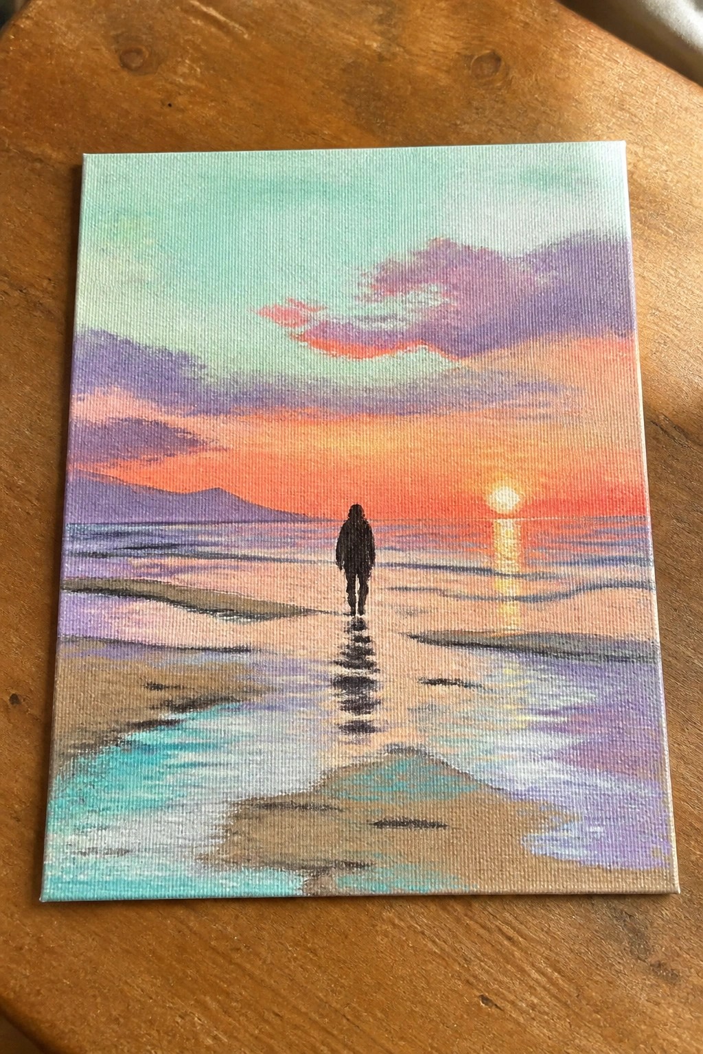 Vibrant canvas painting of silhouetted figure walking toward orange sunset on beach